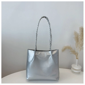 Macro view of metallic silver tote bag featuring unique braided double shoulder straps