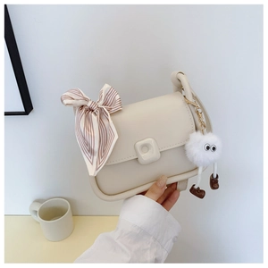Detail of cream crossbody bag with silk scarf and cute plush pendant accessory