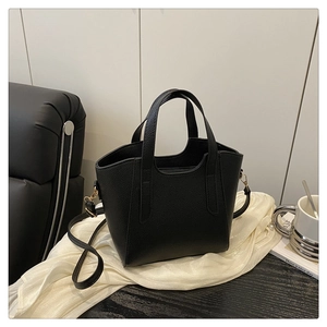 Dettaglio della trama in pelle nera a grana litchi di una borsa a secchiello alla moda