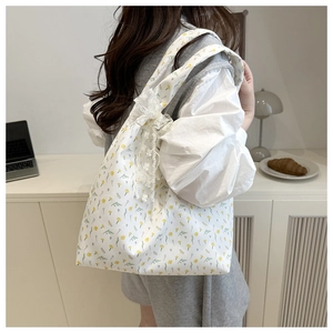 Floral canvas tote bag featuring lace bow accents shown in a cozy lifestyle setting