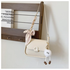 Detail of off-white shoulder bag with silk scarf handle and plush ball charm on rack