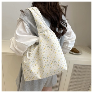 Floral canvas shoulder bag with white lace bow detail shown on a model in a cozy room