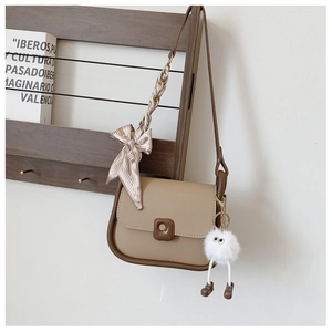 Detail of a beige square crossbody bag with contrast trim and silk ribbon bow accent