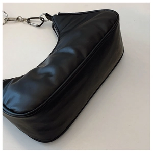 Detail view of glossy black crescent bag showing puff texture and silver metal chain