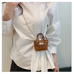 Nahaufnahme von Mini braunem Lederhandtaschen-Anhänger mit Goldkette am Modell