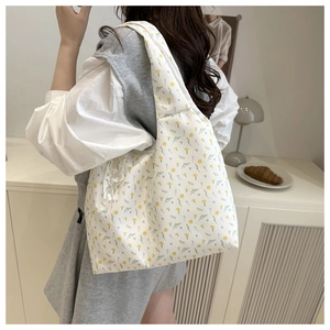 Detail of floral canvas tote bag with yellow flowers and elegant lace pendant