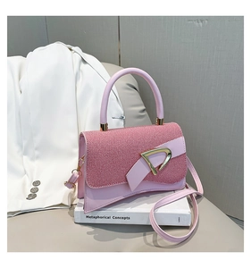 Detail of pink leather handbag featuring a stylish golden D-ring buckle and textured flap