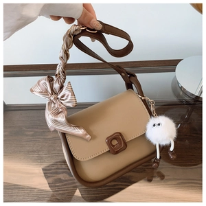 Detail of vintage brown crossbody bag featuring a striped silk scarf and plush charm