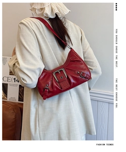 Gros plan du sac à bandoulière rouge vintage avec boucle argentée et texture aspect vieilli