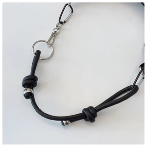 Detailed view of black leather cord handle with silver metal rings and industrial knot detail
