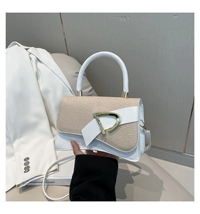 Detail of white leather and beige woven handbag with bow and golden clasp
