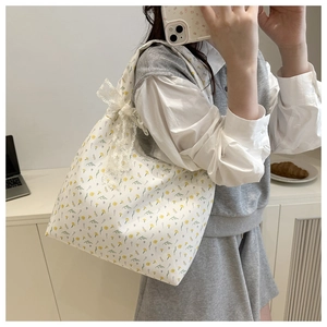 Close-up of floral canvas tote bag with yellow blossoms and lace bow detail