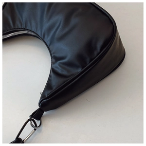 Close-up of black crescent underarm bag showing lychee grain leather and silver metal zipper