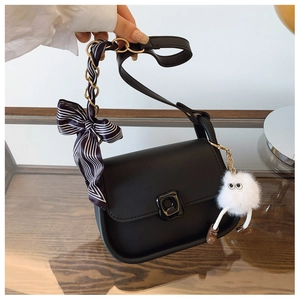 Detail of black matte shoulder bag with silk scarf handle and plush monster charm