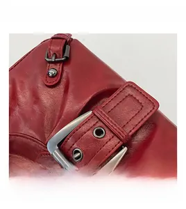 Macro detail of red crescent bag with glossy leather texture and retro metal buckle