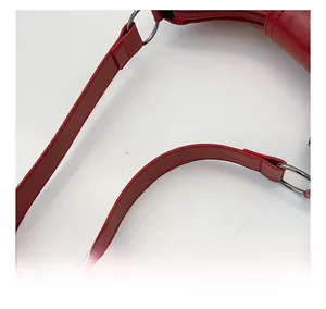 Detail of red shoulder bag showing metal ring buckle and smooth synthetic leather stitching