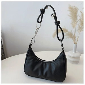Detail of black crescent shoulder bag featuring industrial-style braided rope knot strap