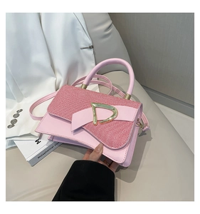 Pink shoulder bag detail showing woven texture with gold D-buckle and hand strap
