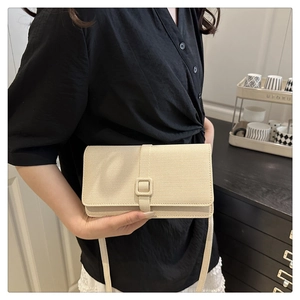 Détail d'un sac bandoulière beige tissé avec boucle rectangulaire et fine sangle réglable