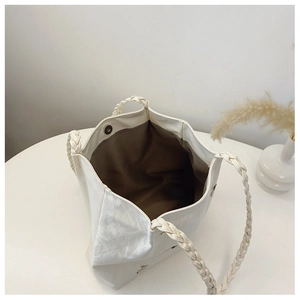 Detail view of large cream tote bag with woven handles and interior magnetic buckle