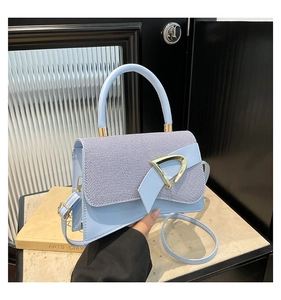 Detail of light blue handbag featuring textured fabric flap and golden D-buckle hardware