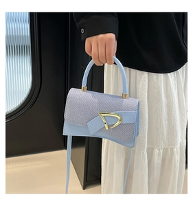 Detail of light blue crossbody bag featuring contrast texture and gold metal hardware