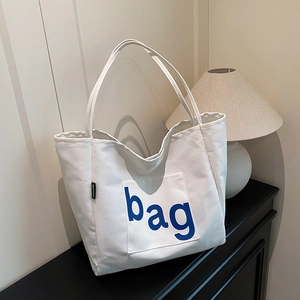 Stylish white canvas tote bag with blue bag letter print and fashion tag on black shelf