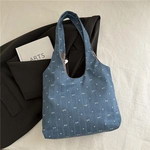 Chic blue tote bag with white bow prints on fabric, styled with lifestyle props