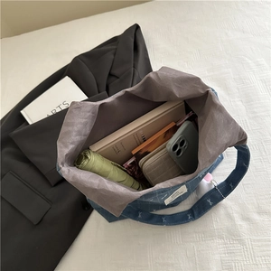 Spacious blue denim tote bag with white bow prints showing interior capacity for essentials