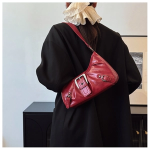 Detail of red vintage-style pleated shoulder bag worn with a black oversized blazer