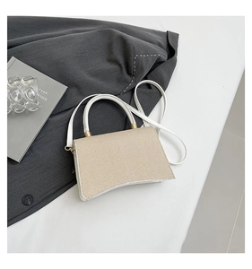 Detail of beige woven hourglass bag with white leather handle and gold hardware