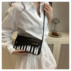 Detail of piano key pattern crossbody bag with I LIKE MUSIC text on smooth leather