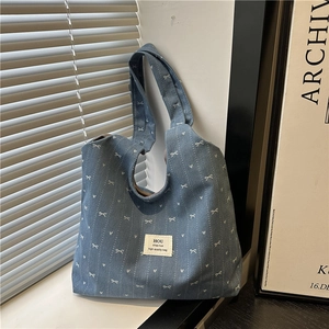 Detail of blue denim tote bag with white bow patterns resting against a sunlit window