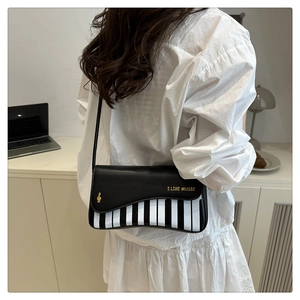 Detail of piano key handbag featuring golden music notes and I LIKE MUSIC slogan