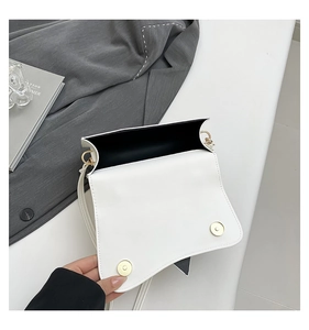 Detailed interior of minimalist white leather crossbody bag with golden magnetic buckles