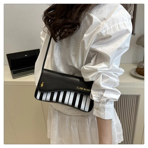 Detail of piano key pattern design and gold music note lettering on a stylish crossbody bag