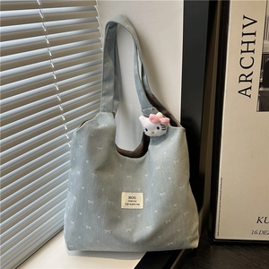 Denim bow tote bag for women with floral pattern and cute cat plush charm on a windowsill