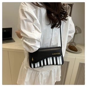 Detail of crossbody bag featuring piano key pattern and gold I LIKE MUSIC print