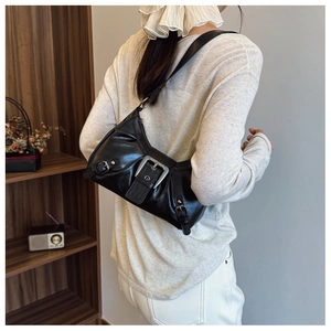 Detail of black glossy shoulder bag with silver buckles and pleated motor style design