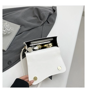 Open view showing internal storage capacity for phone and makeup in white saddle bag