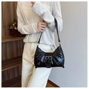 Detail of a black crescent armpit bag with large metal buckle on a shoulder strap