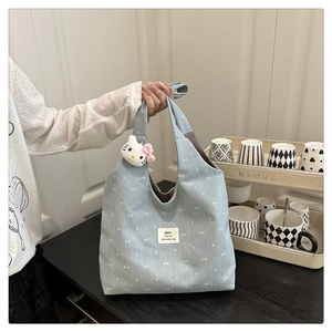 Detail of light blue tote bag with white bow pattern and cute kitten plush keychain