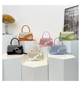 Collection of small crossbody bags in various colors with metallic buckle on white pedestals