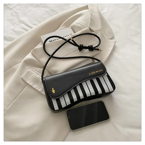 Detail view of piano key crossbody bag featuring gold G-clef and I LIKE MUSIC slogan