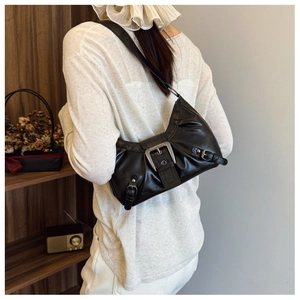 Detail shot of black biker-style shoulder bag with silver buckle and textured leather