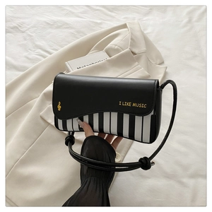 Detail of the piano key pattern and 'I LIKE MUSIC' print on the black crossbody bag