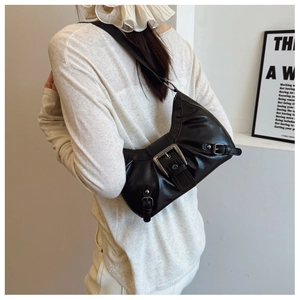 Detail of a vintage black shoulder bag with a large metallic buckle and wrinkled texture
