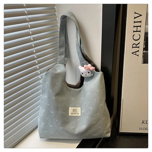 Detail of blue canvas tote bag with heart patterns and a white plush cat charm