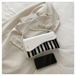 Detail showing white leather piano key pattern bag with gold I LIKE MUSIC text on suit