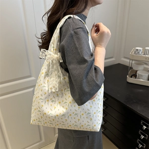 Floral canvas tote bag with white lace bow detail shown on female model shoulder